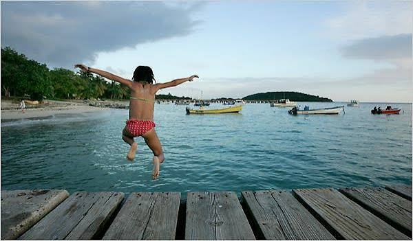 A person jumping from a wooden pier into the bay